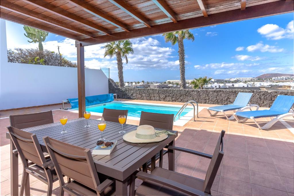 a patio with a table and chairs and a swimming pool at Villa Casa Mar in Playa Blanca