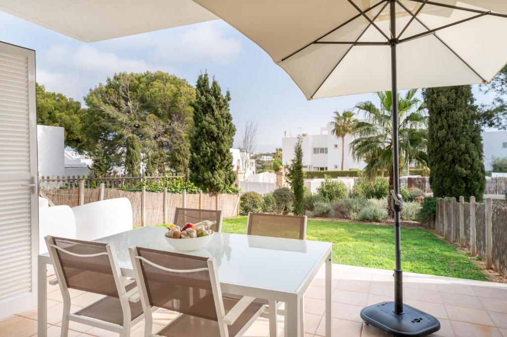 a white table and chairs with an umbrella on a patio at El Puerto I 1-3 in Cala D'or