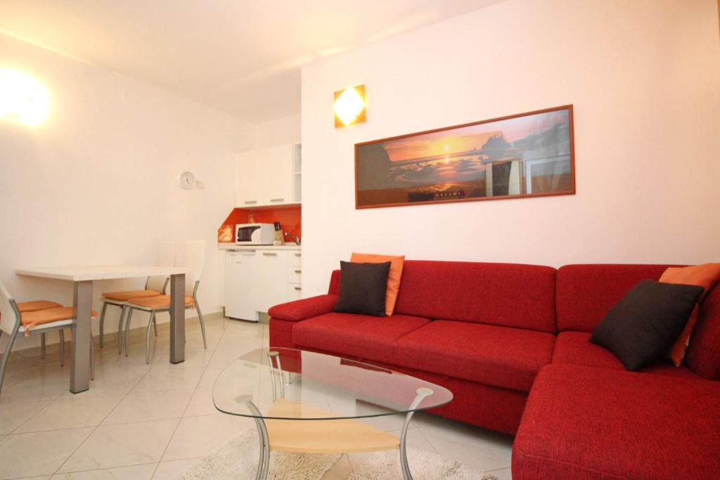 a living room with a red couch and a table at Apartment Krleza in Baška