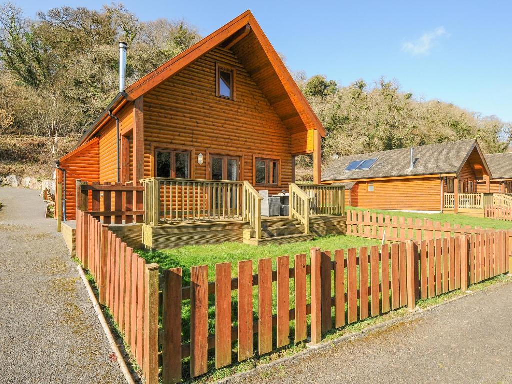 a wooden house with a fence in front of it at Polzeath in Bodmin