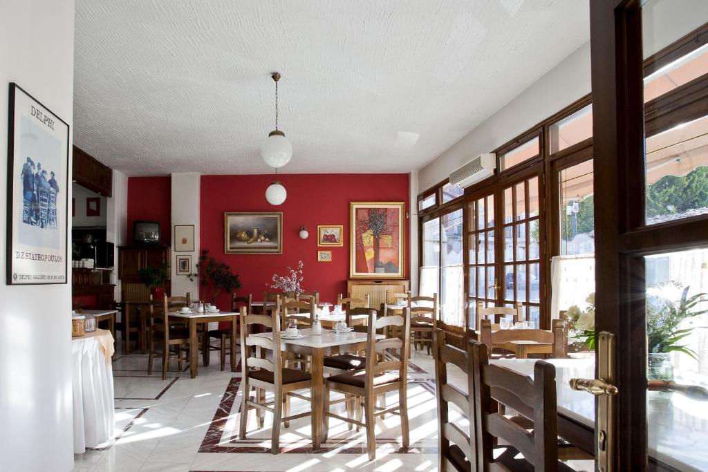 una sala da pranzo con pareti rosse, tavoli e sedie di Kouros Hotel a Delfi