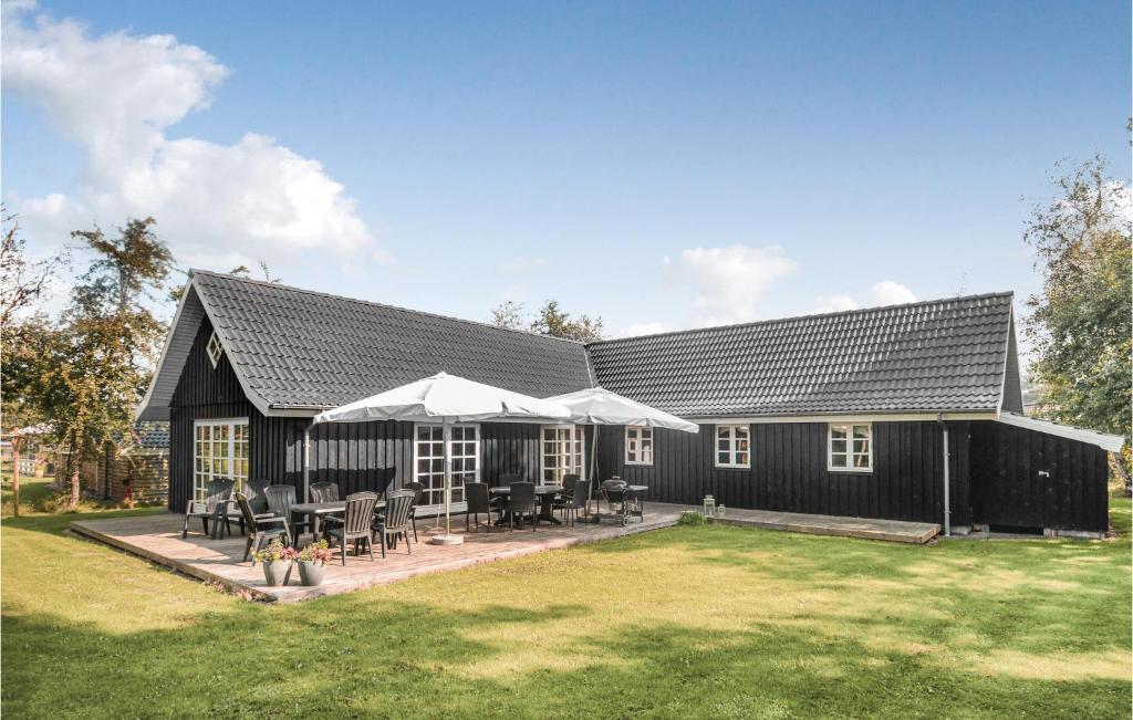 un edificio nero con tavoli e sedie in un cortile di Nice Home In Vggerlse With 4 Bedrooms, Sauna And Wifi a Bøtø By