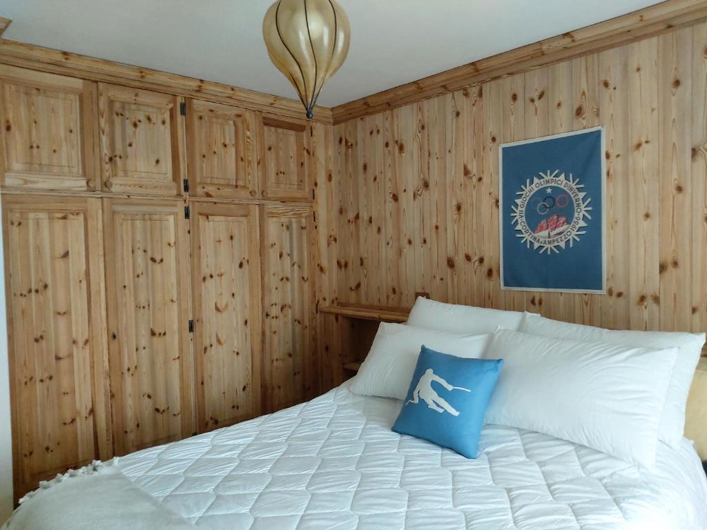 Schlafzimmer mit Holzwänden und einem Bett mit blauen Kissen in der Unterkunft APPARTAMENTO CORTINA 1956 in Cortina d'Ampezzo