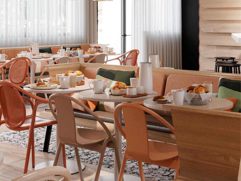 a restaurant with tables and chairs with food on them at ibis Styles Porto Vecchio in Porto-Vecchio