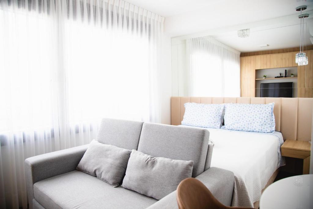 a bedroom with a bed and a couch in front of a window at Studio Boutique in Porto Alegre