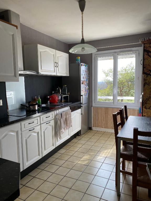 a kitchen with white cabinets and a table and a refrigerator at Maison de Ophelia in Périgné