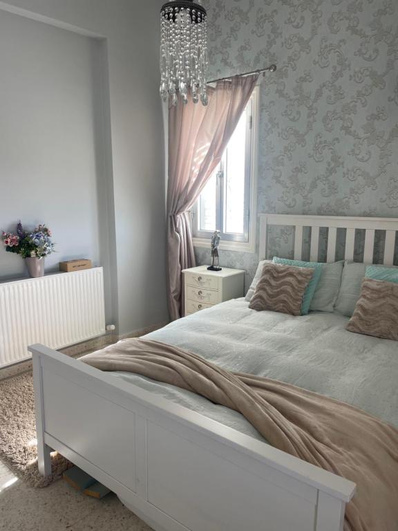 1 dormitorio con cama blanca y lámpara de araña en Pissouri Villa Miramar, en Pissouri