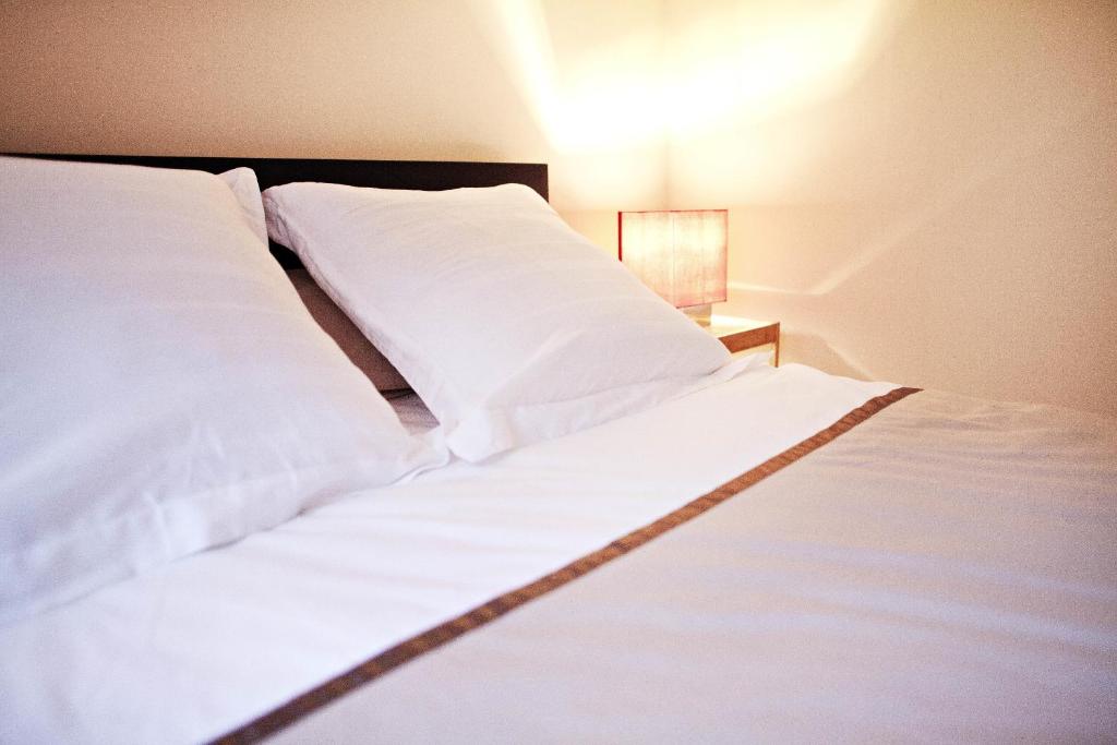 クレルモン・フェランにあるChez Maud et Jcの白いシーツとランプ付きの大きな白いベッド