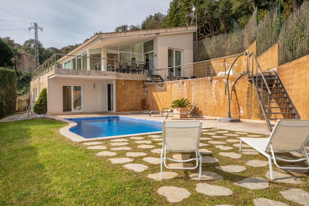 una casa con piscina y 2 sillas en Hauzify I Villa Masclet, en Castillo de Aro
