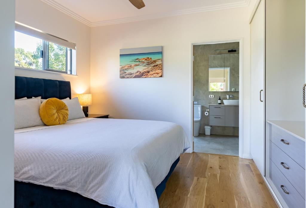 1 dormitorio con 1 cama blanca grande y baño en Lilly Pilly Cottage Margaret River en Margaret River Town