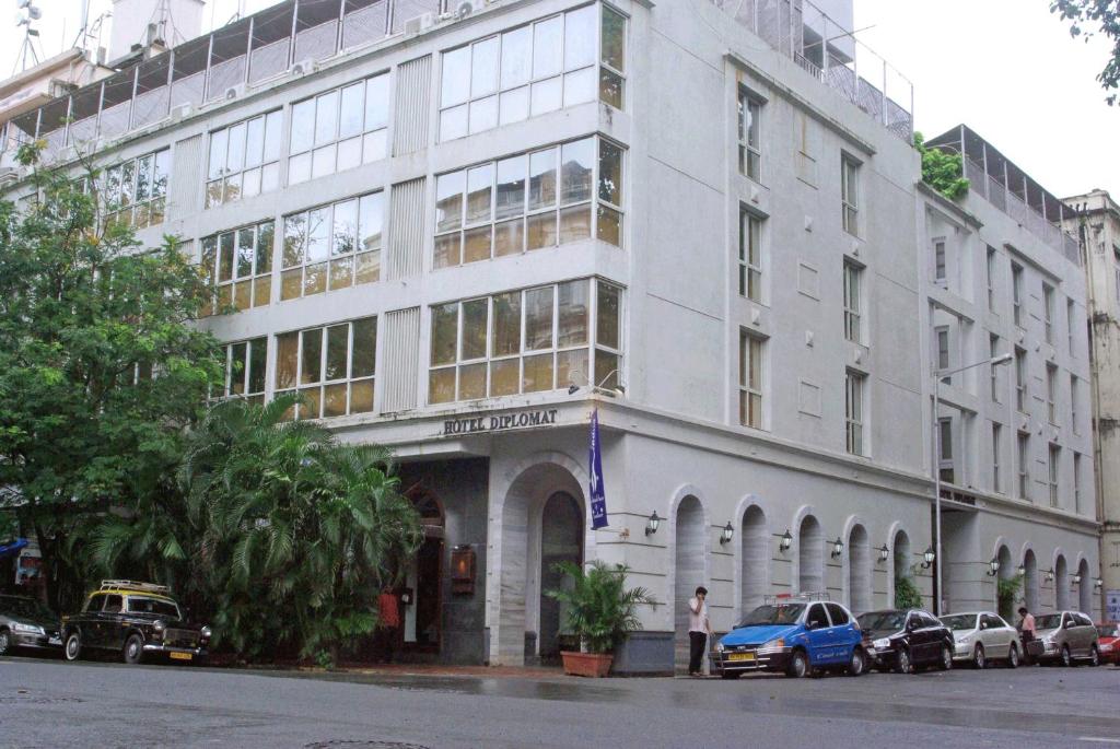 un grande edificio bianco con macchine parcheggiate di fronte di Hotel Diplomat, Colaba a Mumbai