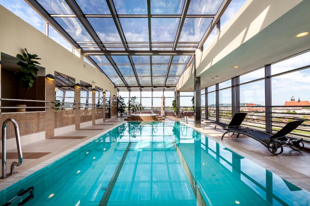 an indoor pool with a glass ceiling and chairs in a building at Qubus Hotel Kraków in Krakow