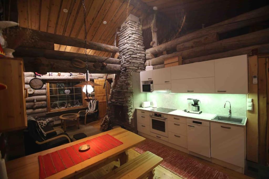 una cucina con tavolo e camino in una baita di tronchi di VIP Luostonkehto, Wi-Fi, ilmastointi a Luosto