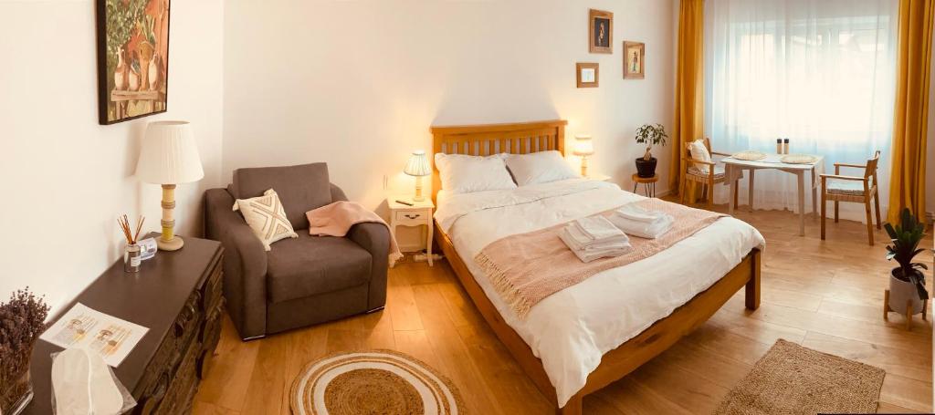 a bedroom with a large bed and a chair at Warm and cozy studio flat near Straja in Uricani