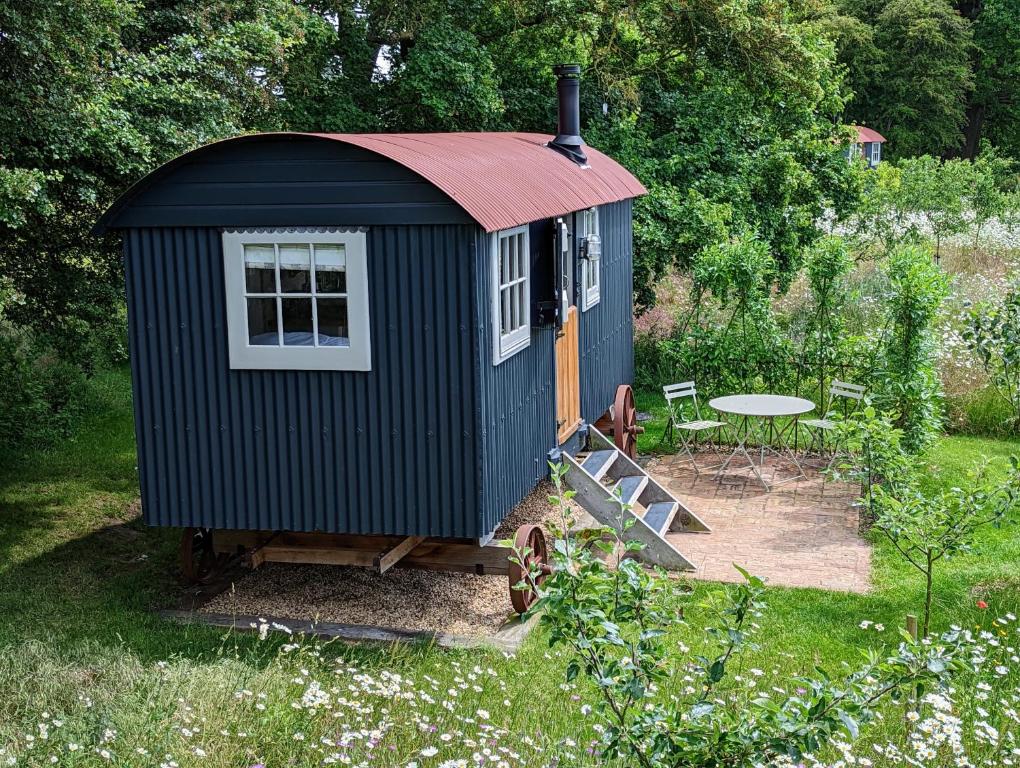 a small shed with a table in a garden at Stamford Cider Huts in Stamford