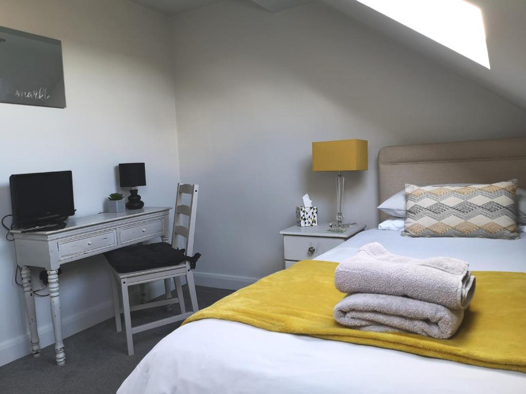 a bedroom with a desk and a bed with towels on it at York City Homestays in York
