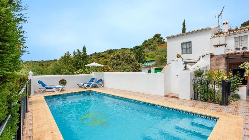 a swimming pool with two blue chairs next to a house at Cortijo los Valles Alozaina by Ruralidays in Alozaina