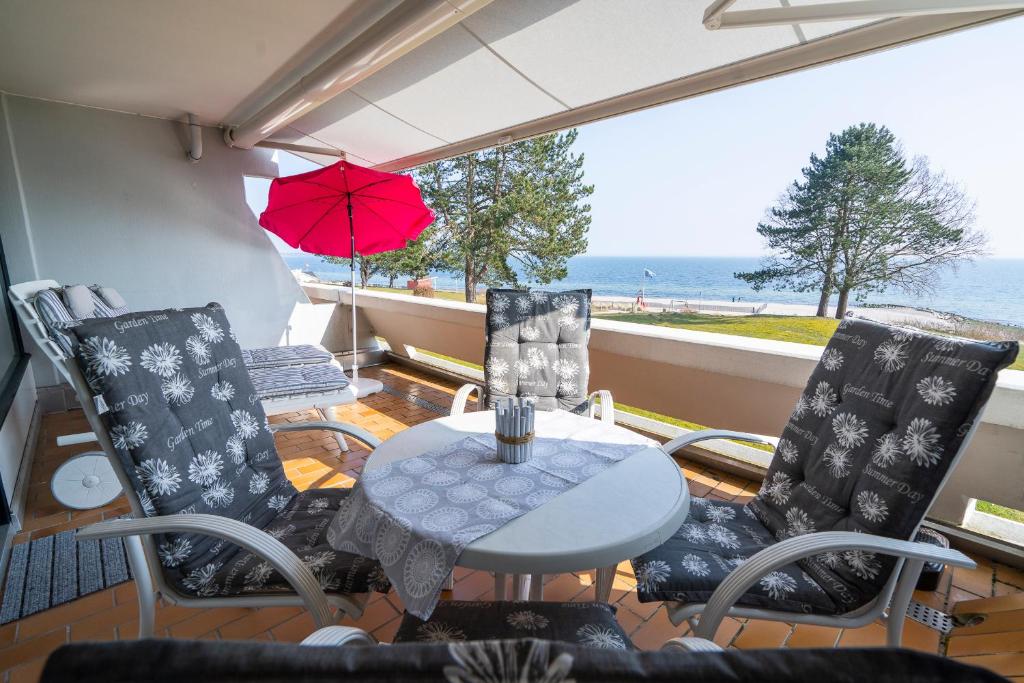a patio with a table and chairs and the ocean at Ferienpark Sierksdorf App 51 - Strandlage in Sierksdorf