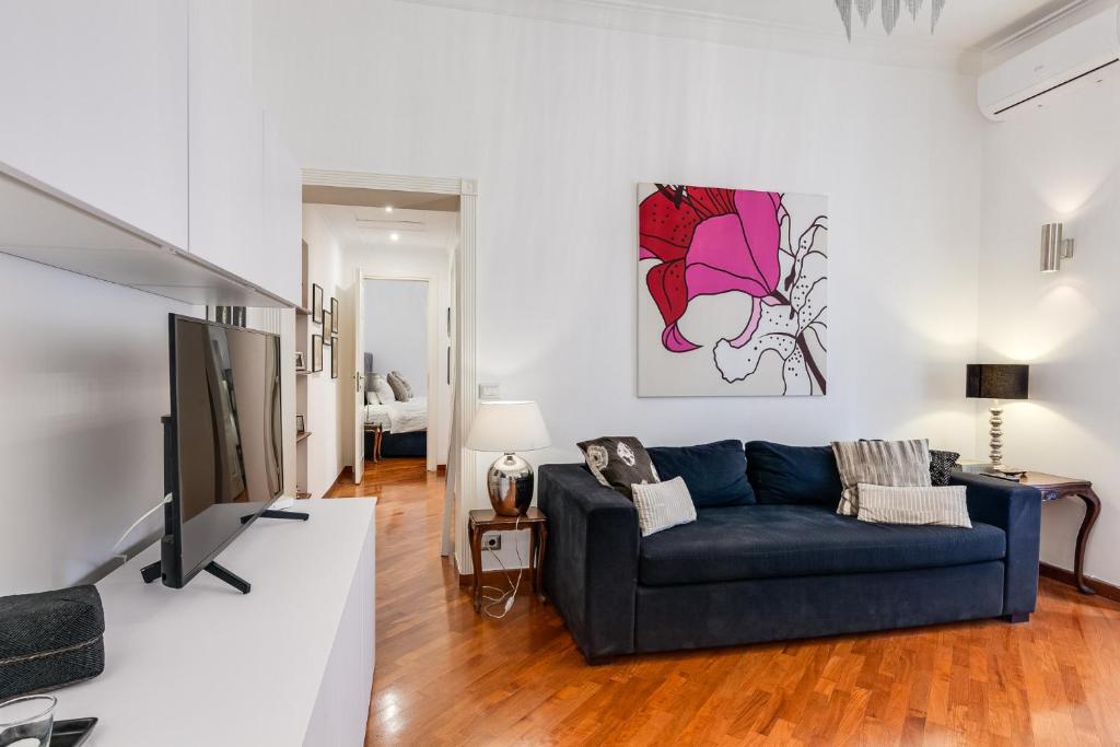 ein Wohnzimmer mit einem blauen Sofa und einem TV in der Unterkunft S. Cosimato Trastevere in Rom