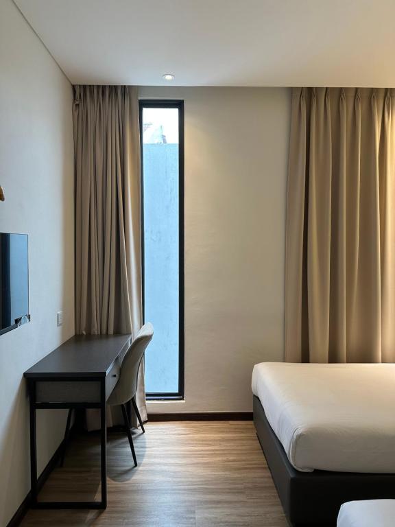 um quarto de hotel com uma secretária, uma cama e uma janela em The Gallivant Hotel em George Town