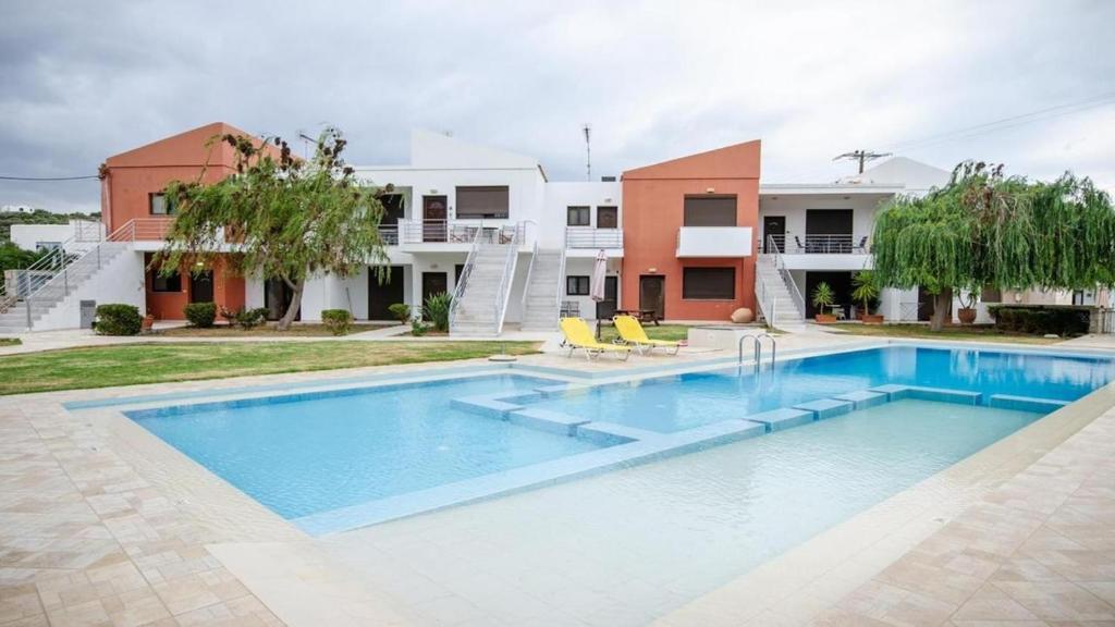 a swimming pool in front of a house at Mati- Cozy apartment- Close to the beach of Almyrida with a shared Pool in Chania