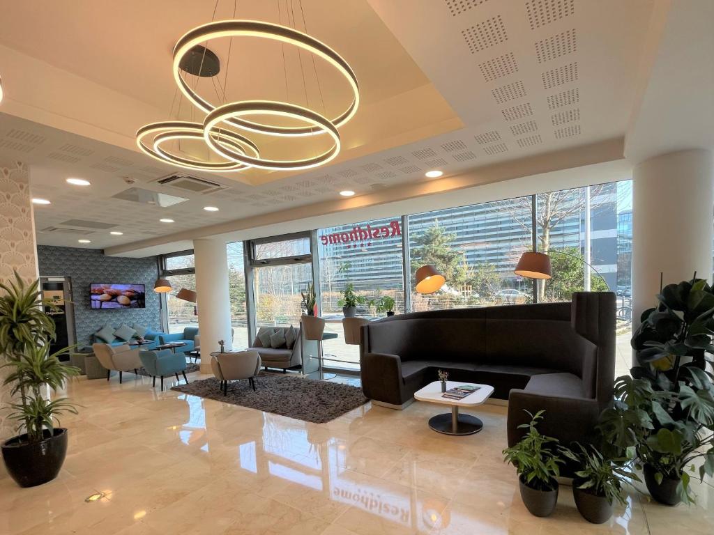 eine Lobby mit einem Wartebereich mit Pflanzen und einem Kronleuchter in der Unterkunft Residhome Paris Issy Les Moulineaux in Issy-les-Moulineaux