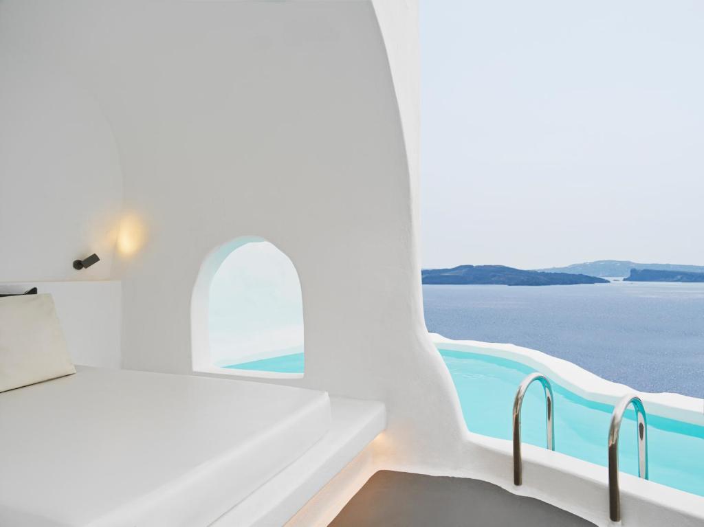 a white room with a view of the ocean at Katikies Santorini - The Leading Hotels Of The World in Oia