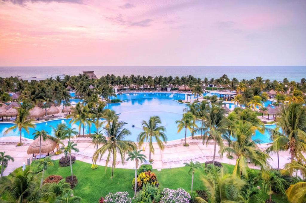 an aerial view of a resort pool with palm trees and the ocean at Resort Vidanta Riviera Maya in Puerto Morelos