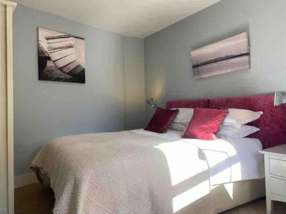 una camera da letto con un grande letto bianco con cuscini rossi di Flat2BeckfordMews a Cowes