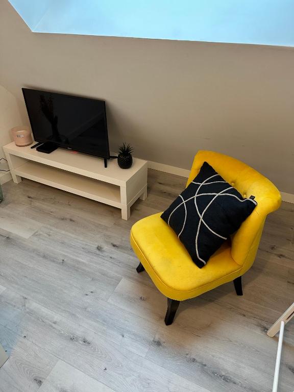 a living room with a yellow chair and a television at L&#39;ENSOLEILLÉ - Classé 2 étoiles - Nay centre - Appartement in Nay