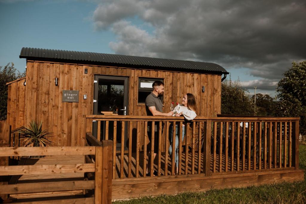 a man and woman standing on the balcony of a tiny house at The Ginger Nut in Welshpool