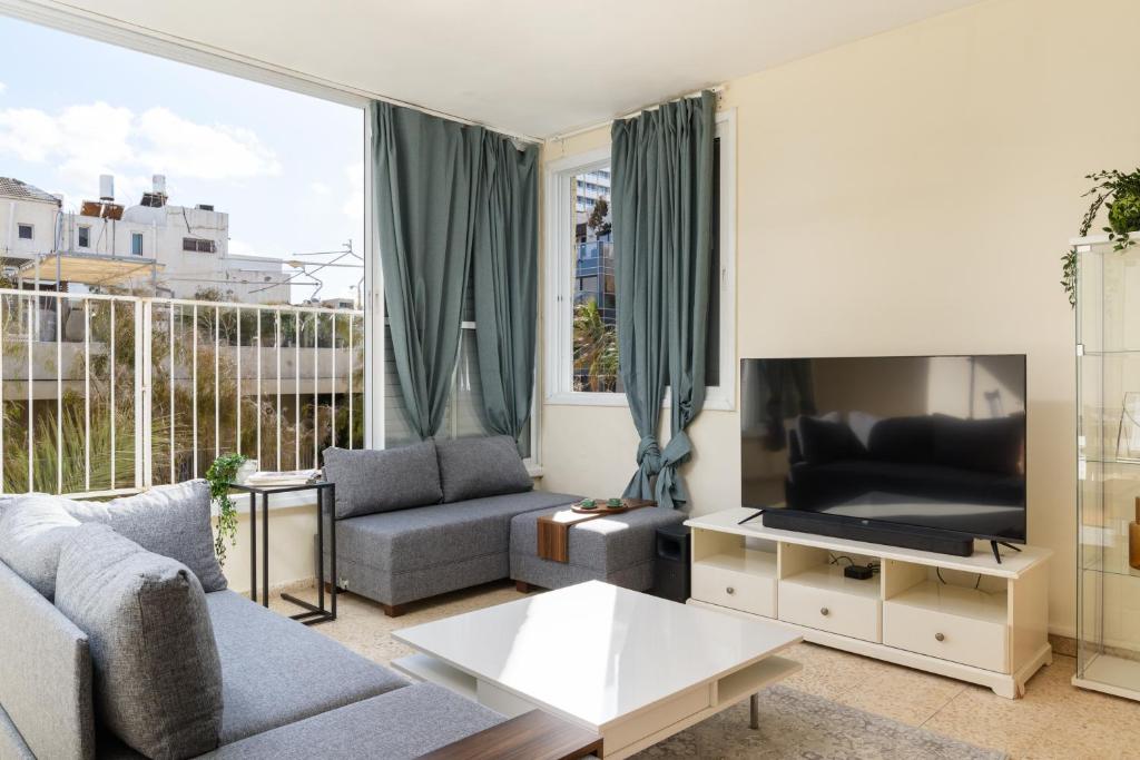 a living room with a couch and a tv at Gordon Seaside 4BDR apt in TLV in Tel Aviv