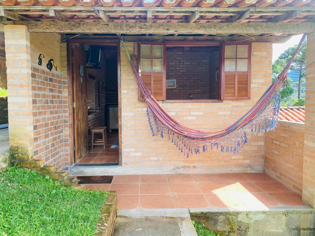 a brick house with a hammock on the side of it at Chalé buraco do tatu in Conceição da Ibitipoca