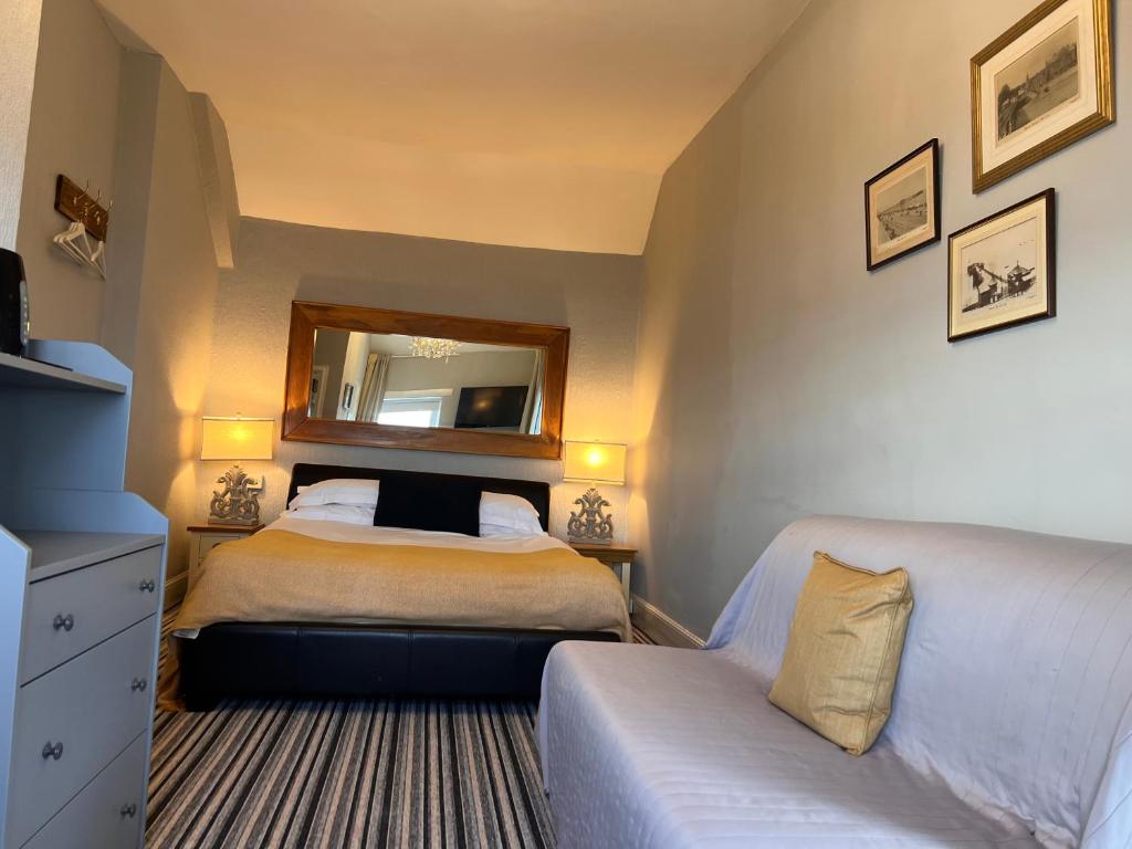 1 dormitorio con cama, espejo y sofá en Sids restaurant and bar with rooms en Cardiff