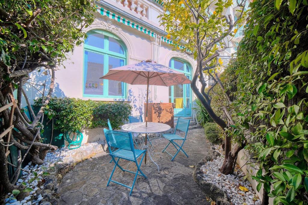 une table et des chaises avec un parasol sur une terrasse dans l'établissement IMMOGROOM -Terrace with garden - Quiet - Air-conditioner, à Cannes