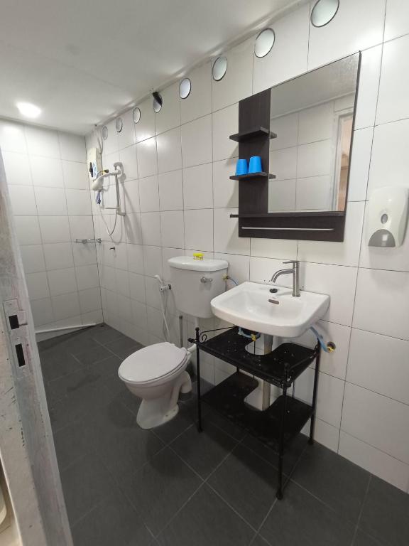 a white bathroom with a toilet and a sink at Tiongman Scubadive & Lodge in Tioman Island