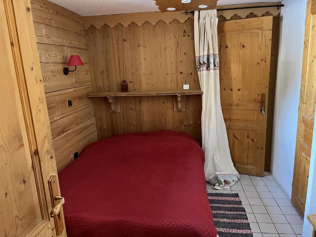 a bedroom with a red bed in a room with wooden walls at Chalet la Grande Motte in Champagny-en-Vanoise