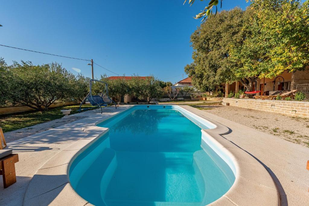 a swimming pool with blue water in a yard at Holiday home Apios in Benkovac
