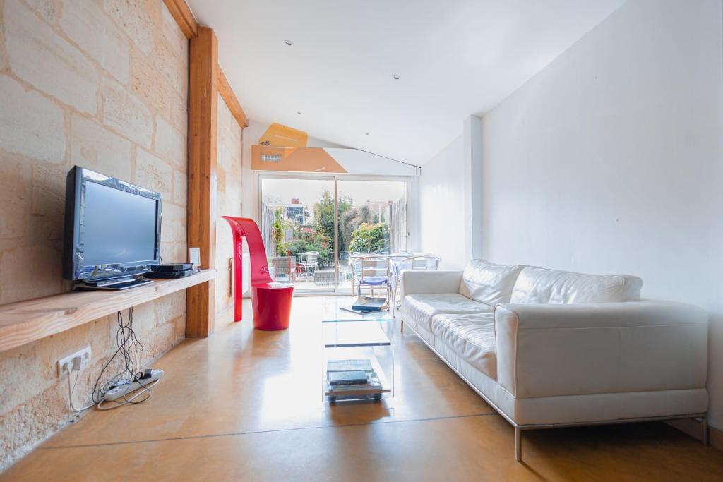 a living room with a couch and a tv at Maison spacieuse avec Jardin et Garage in Bordeaux