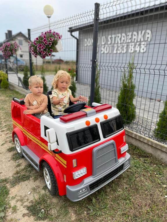 two children riding in a toy fire truck at DOMKI U STRAŻAKA GĄSKI -MORZE in Gąski