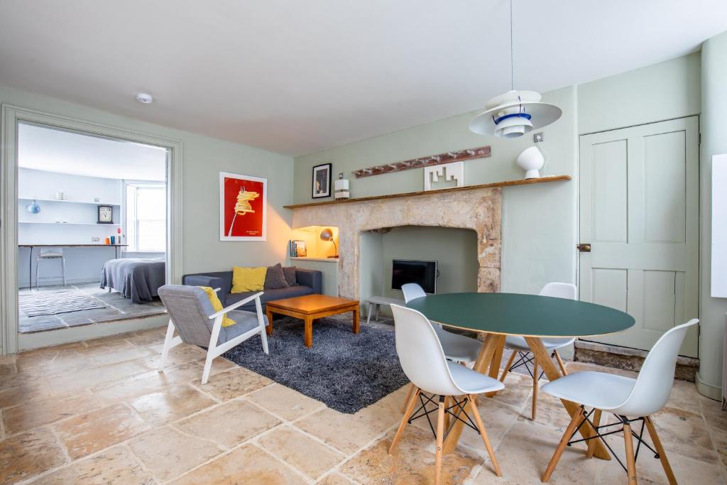 sala de estar con mesa, sillas y chimenea en Walcot Apartment, en Bath