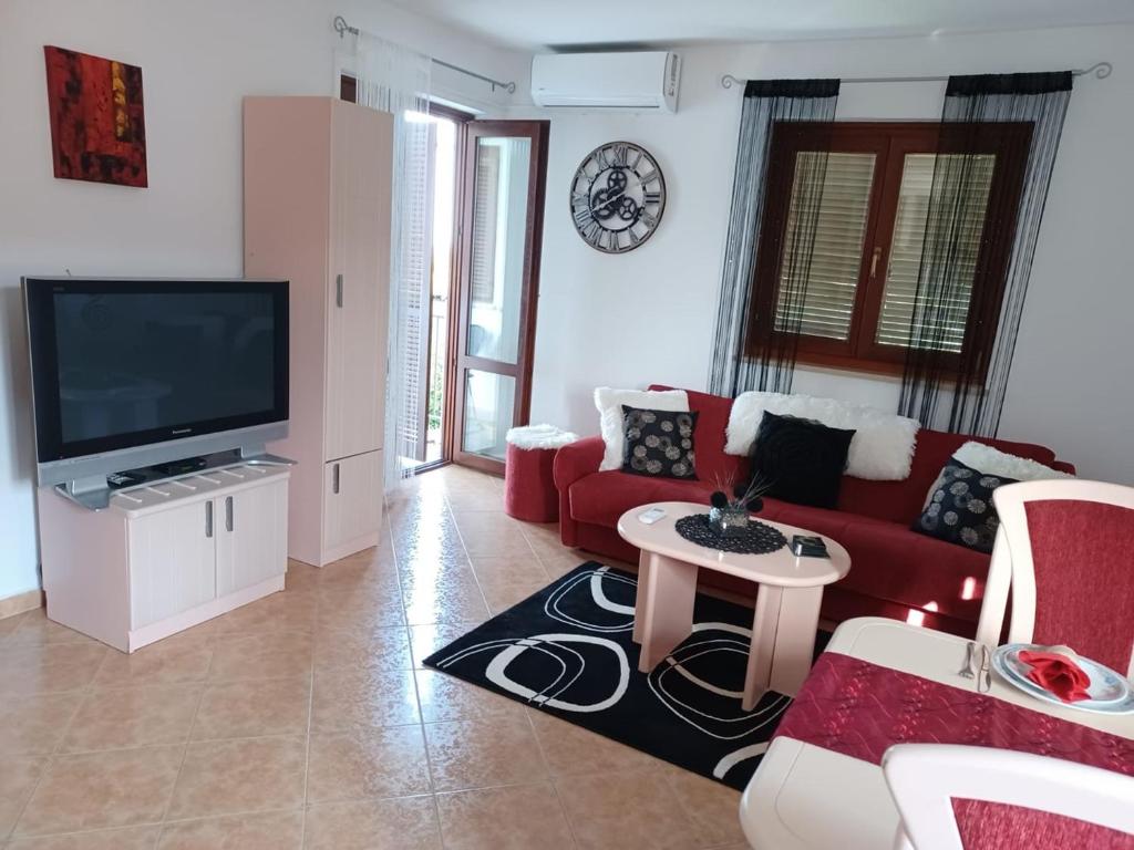 een woonkamer met een rode bank en een tv bij Lovely Apartment Piantade in Poreč