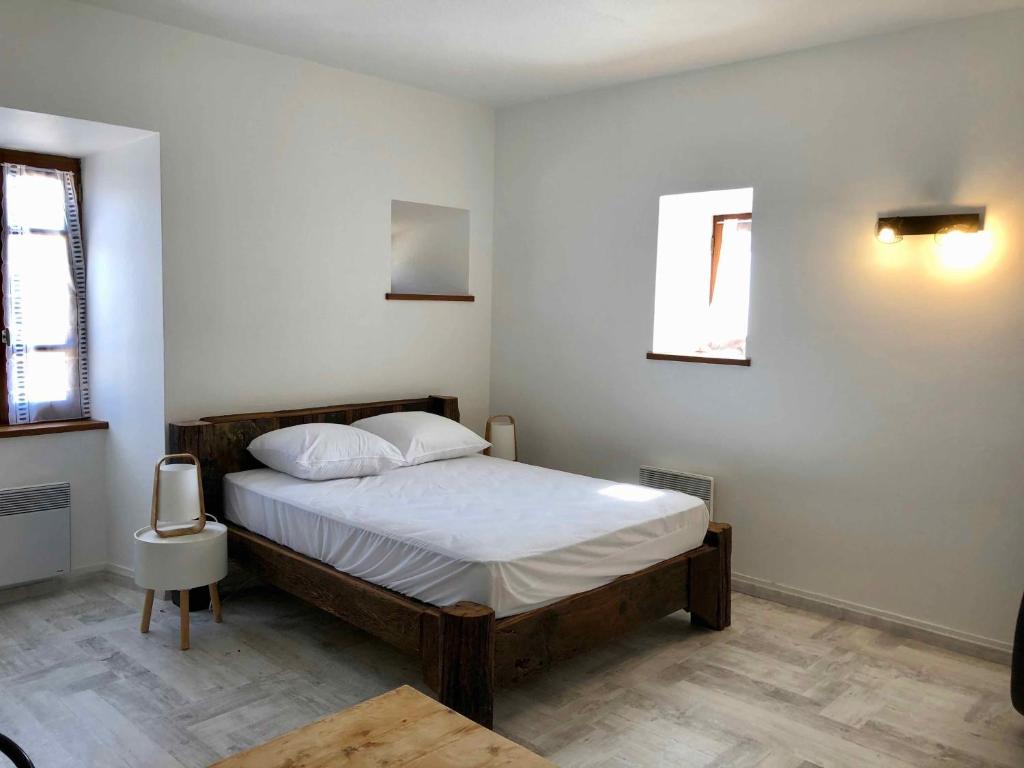 a bedroom with a bed with white sheets and a window at Auberge Les Grillons in Meyras