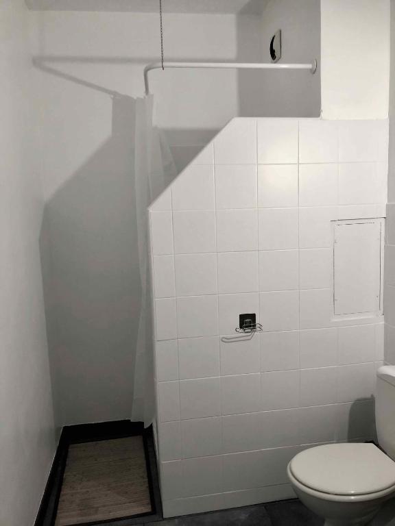 a bathroom with a toilet and a white tile wall at Auberge Les Grillons in Meyras