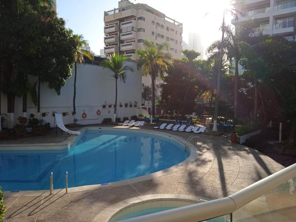 a swimming pool with chairs and a building at Hotel Bahia Cartagena in Cartagena de Indias