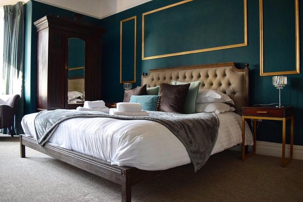 a bedroom with a large bed with blue walls at Blakeney House in Blakeney