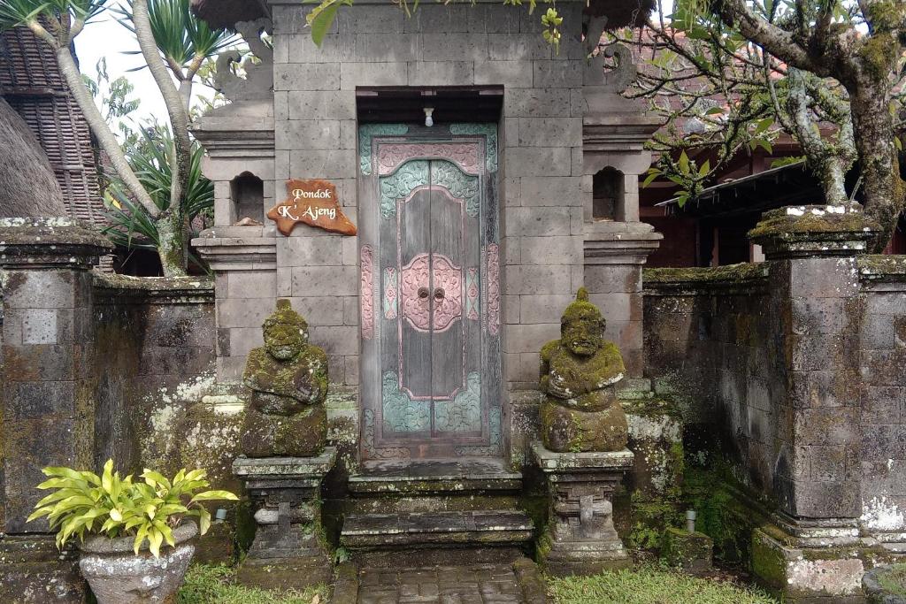 una puerta en un edificio de piedra con dos estatuas delante en Villa Adhi Rajasa, en Penebel