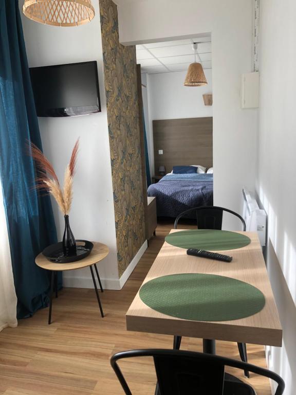 a room with two tables and a bed at Résidence Cosyade équipée d'un parking privé gratuit in Bourbourg