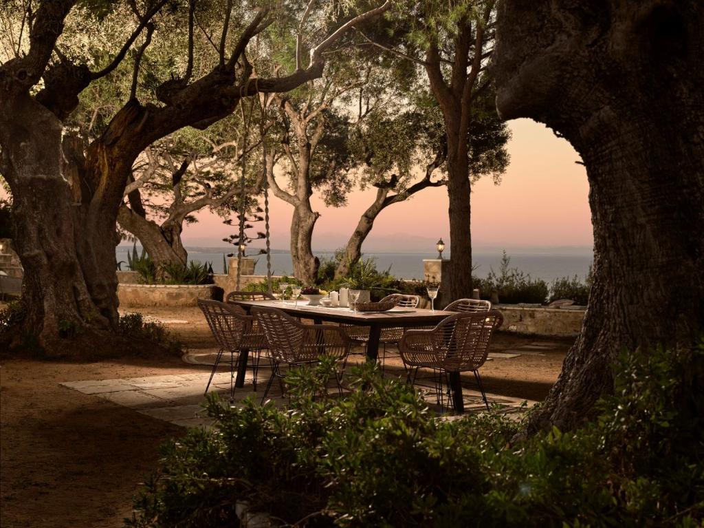 a table and chairs in a park with trees at Villa Anatoli - Tranquil Escape with Scenic Views, by ZanteWize in Akrotiri