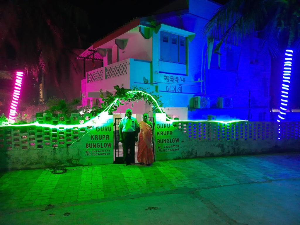 two people standing in front of a house with lights at Gurukrupa Bunglow in Dwarka